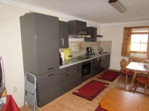 a kitchen with gray cabinets and a table and a dining room at Ferienwohnung Öderhof in Saaldorf