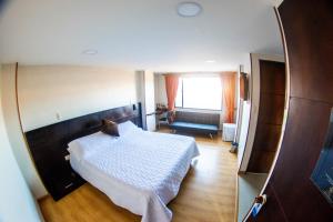 a bedroom with a white bed and a mirror at Hotel Plaza Muisca in Tunja