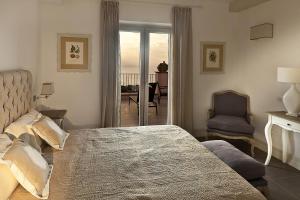 a bedroom with a bed and a chair and a balcony at Tenuta Del Poggio Antico in Ischia