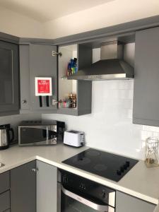 a kitchen with gray cabinets and a stove top oven at Great Georges Apartments In association with Great Georges Duplex apt for larger groups in Warrenpoint