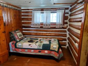 1 dormitorio con 1 cama en una cabaña de madera en Chinook Cabins & RV Park, en South Fork