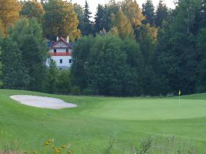 un campo de golf verde con una casa en el fondo en Penzion Vital en Liberec