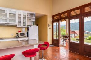 a kitchen with red chairs and a counter with a refrigerator at Casa Bartzis, every stay comes with a free professional massage in Orosí