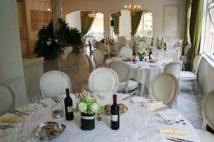 a restaurant with white tables and white chairs and wine bottles at Hotel La Pigna in Marina di Pietrasanta