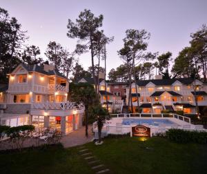 uma casa grande com uma piscina em frente em Miradores del Bosque Apart & Spa em Mar de las Pampas