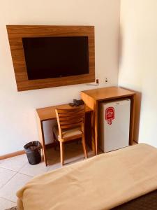 een kamer met een bureau, een televisie en een stoel bij Parque Hotel Holambra in Holambra