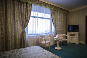 a hotel room with a bed and a table and a window at Pensiunea Crystal II in Valea Lupului