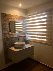 a bathroom with a sink and a window with blinds at HOTEL COLIBRÍ in Creel