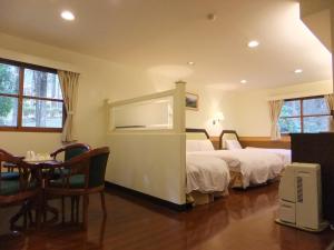 ein Hotelzimmer mit 2 Betten und einem Tisch in der Unterkunft Xitou Youth Activity Center in Lugu