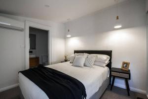 um quarto com uma cama grande com lençóis brancos e almofadas em The Mistress em Launceston