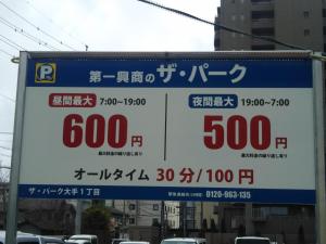 Una señal para un estacionamiento con precios. en Matsumoto BackPackers, en Matsumoto