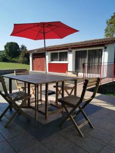 a wooden table and chairs with a red umbrella at Askatasuna in Itxassou