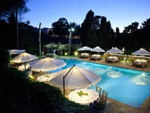 a swimming pool with tables and umbrellas at night at Agriturismo Baglio Fontana in Buseto Palizzolo