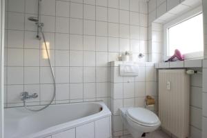 a white bathroom with a tub and a toilet at RAJ Living - 1 , 3 and 4 Room Apartments - 20 min Messe DUS & Airport DUS in Meerbusch