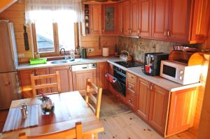 a kitchen with wooden cabinets and a table and a microwave at Cichy Zakątek in Ujsoły