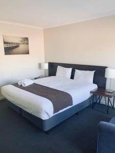 a bedroom with a large bed and a chair at Sunshine Motor Inn in Ardeer
