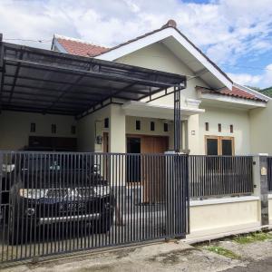 a house with a black fence in front of it at Choko Homestay in Tjolomadu