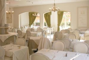 a banquet hall with white tables and chairs at Hotel La Pigna in Marina di Pietrasanta