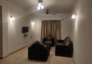 a living room with two chairs and a tv at Areia De Goa - SunLight By Leela Homes in Arpora