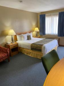 a hotel room with a large bed and a chair at Thunderbird Motor Lodge, Norman, OK in Norman