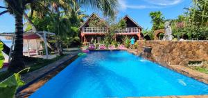 a swimming pool in front of a house at Hotel ECOLODGE LE RAVORAHA in Sainte Marie
