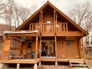 a large wooden cabin with a porch and a deck at Betsu Inn in Hakuba