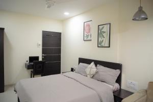 a bedroom with a white bed and a desk at Lite Stays - Vile Parle East in Mumbai