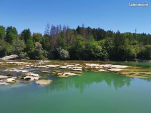 un lac avec des rochers dans l'eau et des arbres dans l'établissement Charmant appartement dans maison de village, à Mesnois