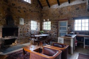 a living room with chairs and a table and a fireplace at Kliphuis in Van Reenen