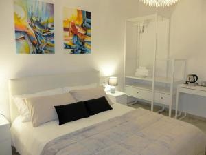 ペスキエーラ・デル・ガルダにあるCamere AME'の白いベッドと壁に絵画が飾られたベッドルーム1室