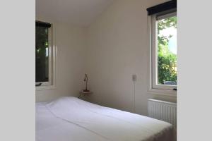 a white bedroom with a bed and two windows at Chalet Bergen NH, Schoorl, Schoorldam in Warmenhuizen