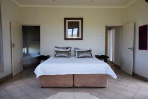 1 dormitorio con 1 cama grande y baño en Highlands Farm House, en Van Reenen