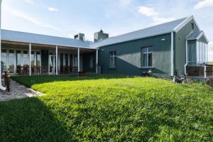 una casa con un césped verde delante de ella en Highlands Farm House, en Van Reenen