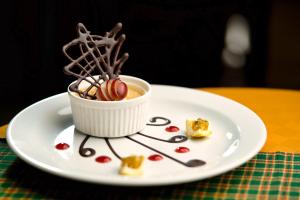 un plato blanco con una taza de postre en una mesa en Kibo Palace Hotel Arusha, en Arusha