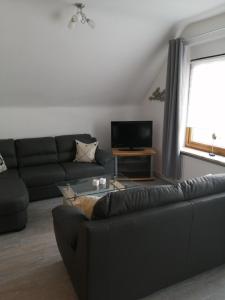 ein Wohnzimmer mit einer schwarzen Couch und einem Fernseher in der Unterkunft Steinmarner Bude in Cuxhaven