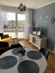a living room with a table and a clock on the wall at Apartamenty nad Bałtykiem in Kołobrzeg