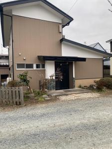 a house with a black door on a street at 民泊ドリームルーカー in Haranomachi