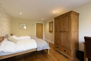 a bedroom with two beds and a large wooden cabinet at Clubhouse Cottage in Lacock