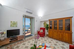 un salon avec une télévision et un fauteuil rouge dans l'établissement Your home in the heart of Positano - centralissima, à Positano