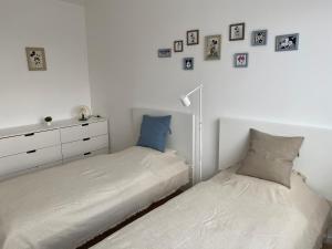 - 2 lits dans une chambre avec des photos sur le mur dans l'établissement OpusTisza7 Apartman, à Tiszafüred