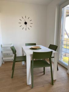 a white table with chairs and a clock on the wall at OpusTisza7 Apartman in Tiszafüred