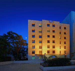 un edificio de hotel con un cartel en él por la noche en Caesar Premier Jerusalem Hotel en Jerusalén