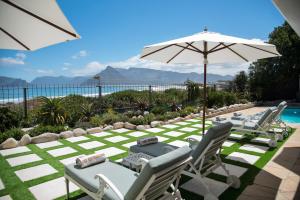 a patio with chairs and an umbrella and a pool at Last Word Long Beach in Kommetjie