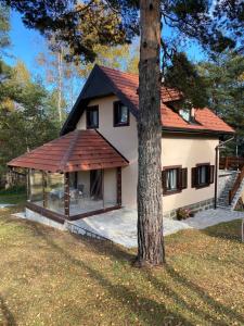 une maison avec un toit rouge et un arbre dans l'établissement Apartman Toki, à Divčibare