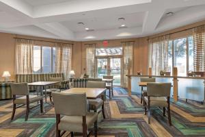 a waiting room with tables and chairs and windows at La Quinta by Wyndham Ft. Lauderdale Airport in Hollywood