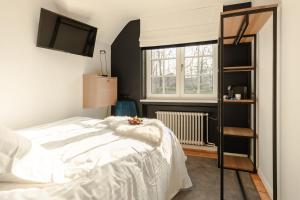 a bedroom with a white bed and a television at Villa Monceau Louvain la neuve in Louvain-la-Neuve