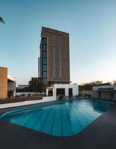 a large swimming pool in front of a tall building at Hotel Kasturi Orchid in Pāl