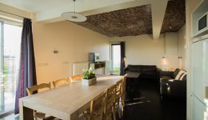 a kitchen and living room with a large wooden table at De Grote Linde in Oostkamp