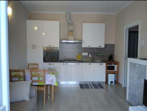 uma cozinha com armários brancos, uma mesa e um sofá em Danilo Apartments em Baveno
