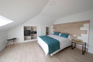 a white bedroom with a bed and a television at Hotel VIDA Finisterre Centro in Finisterre